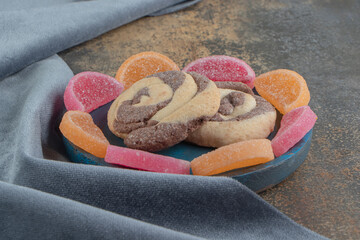 Two cookies in the middle of marmelades circle on a plate on wooden background