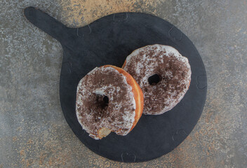 Donuts on a black wooden board on wooden background