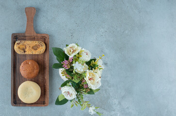 Small bundle of pastries on a small tray next to a vase of flowers on marble background