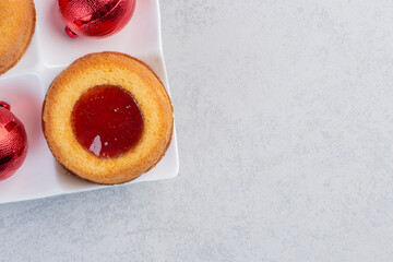 Christmas baubles and jelly-filled cakes on marble background