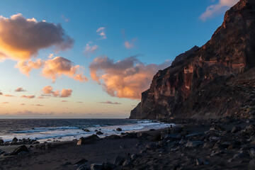 Scenic view during sunset on the volcanic sand beach Playa del Ingles in Valle Gran Rey, La Gomera, Canary Islands, Spain, Europe. Massive cliffs of the La Mercia range. Calm atmosphere at the seaside