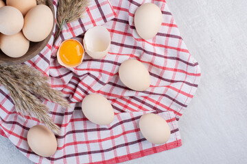 Eggs and feather grass stalks in and next to a bowl on a towel on marble background