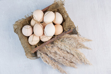 Basket of leaves and a bundle of feather grass stalks on marble background