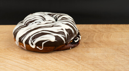 bun covered with chocolate, on a wooden board