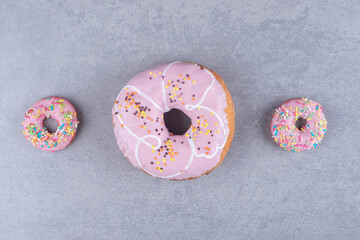 Large and small glazed donuts on marble background