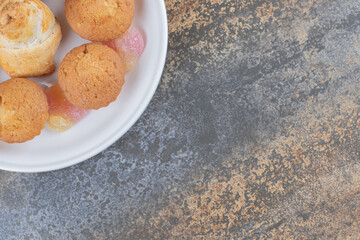 Dessert platter of cupcakes and marmelades displayed on wooden background