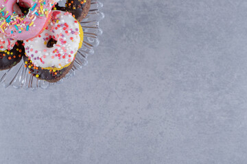 Glass platter with a stack of donuts on marble background