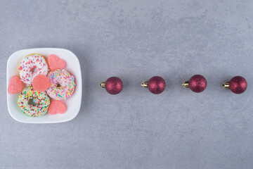 Christmas baubles and a dessert platter lined up on marble background