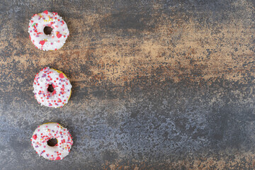 Obraz na płótnie Canvas Three donuts lined in a row on wooden background
