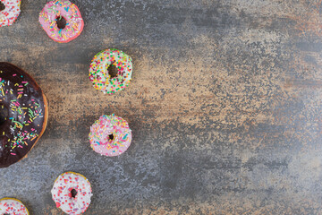 Bite-sized donuts surrounding one big donut on wooden background
