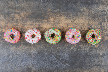 Five donuts lined in a row on wooden background