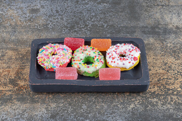 A small, wooden platter with bite-sized donuts and marmelades on wooden background