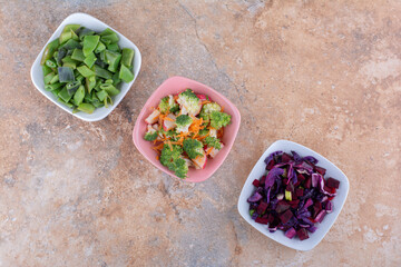 Chopped vegetables mixed and bundled in bowls on a towel on marble background