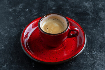 Fresh aromatic morning coffee in red cup on a black background, closeup