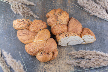 Sliced loaf of strucia bread and bundle of wheat stalks on marble background