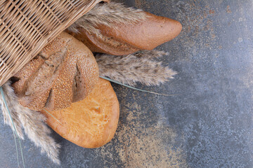 Basket of bread loaves and feather grass stalks on marble background