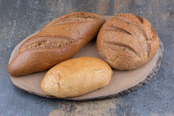 Variety of bread types on a wooden board on marble background