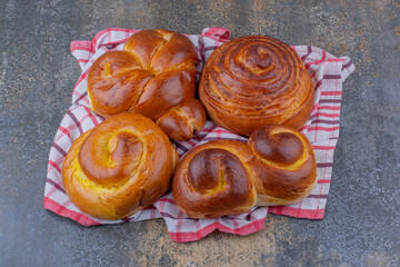 Sweet buns bundled up on a wrinkled towel on marble background
