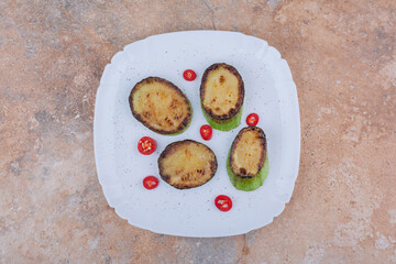Fried zucchini slices and pomegranate arils on a platter on marble background