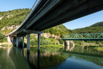 Fototapeta na wymiar Two bridges over the river - one railway and one traffic bridge. Reflections in the water.