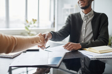 Close up of young black man shaking hands with HR manager while greeting each other at job interview