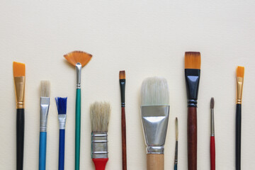 Different artistic paint brushes on paper background. Free space for text