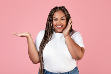 African Obese Woman Holding Invisible Product On Hand, Pink Background