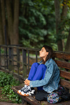 Pensive woman sitting on a bench in a park looking away
