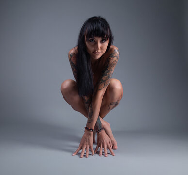 Photo of the nude girl with tattoo sitting on the floor