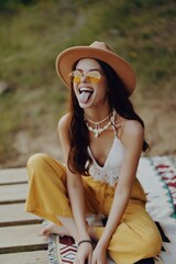 Girl in hippie clothes ridiculously crooked showing her tongue sitting in nature in harmony with...