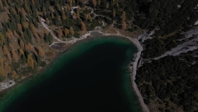 Aerial View Over Seebensee Austrian Alps| Blue Glacial Lake with Tall Mountains and Orange Forest on a Sunny Blue Sky Day