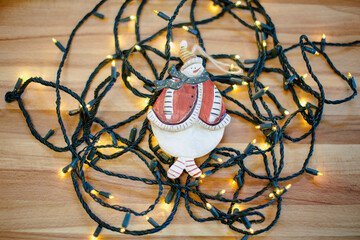 Hand painted wooden snowman on christmas lights and wooden table.