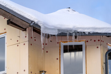 Icicles on roof of private house resulting from improper construction of roof. Metal Downpipe...