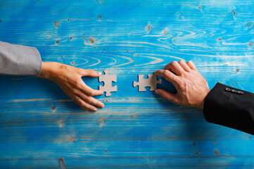 Hands of businesswoman and businessman holding matching puzzle pieces
