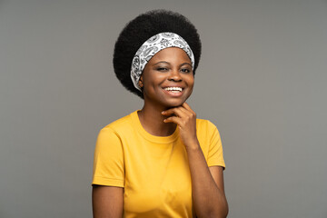 Happy African young woman wearing headband on kinky hair and yellow t-shirt demonstrates positive...