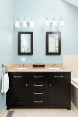 A bathroom with blue walls, a dark wood vanity cabinet, marble countertops, and tiled floors.