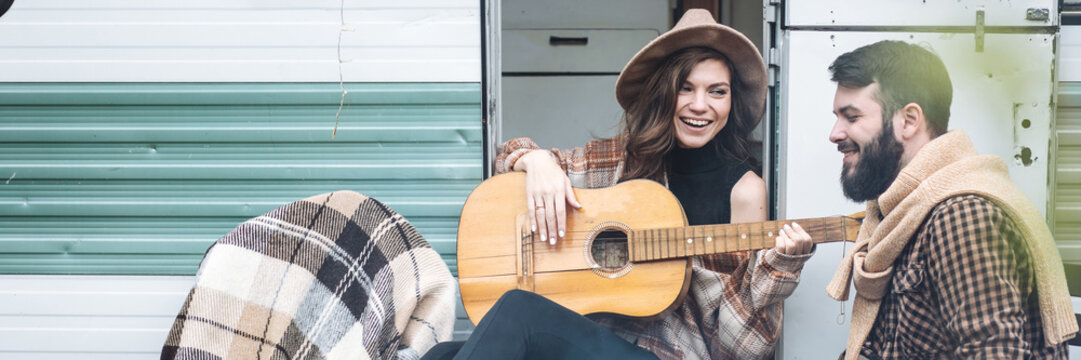 Young beautiful loving couple travelling across country in the van. Millennial man and woman in a travel camper. Cozy atmosphere, vacations vibe. Banner copy space - Powered by Adobe