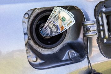 Dollars banknotes sticking out of the gas tank of a car