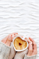 Fototapeta Top view on woman and man hands with cup of hot coffee with cinnamon heart. Symbol of love. Winter and Valentine's Day background with copy space. obraz