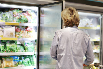 Young man shopping in supermarket, reading product information
