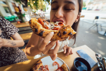 Charming young beautiful woman is eating pizza.
