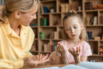 Clever little girl counting on fingers, studying with private teacher at home, kid sitting at desk with female tutor