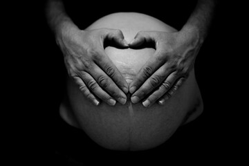 Barriga de embarazada con manos haciendo un corazón.