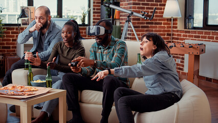 Multiethnic group of friends feeling sad about lost gaming competition, playing video games and losing with virtual reality headset. People being frustrated about lose at party gathering.