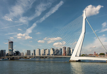 Rotterdam, Netherlands - July 11, 2022: Erasmusbrug, bridge. Landscape, South landing under blue cloudscape. New high rise achitecture on Boompjeskade other side of New Meuse river