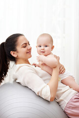 mother playing with her baby girl on a fitness ball