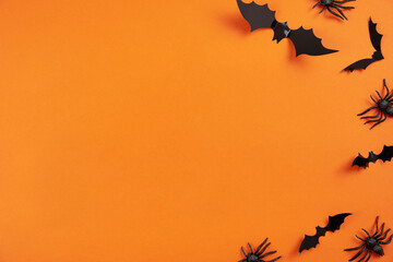 Happy halloween flat lay mockup with black spiders and bats on orange background. Holiday concept composition. Top view. Copy space.