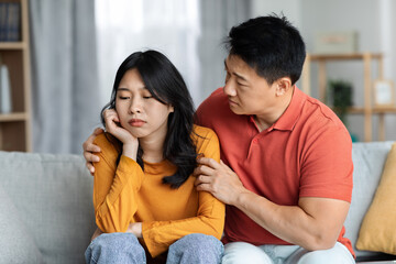 Loving asian husband comforting his upset wife