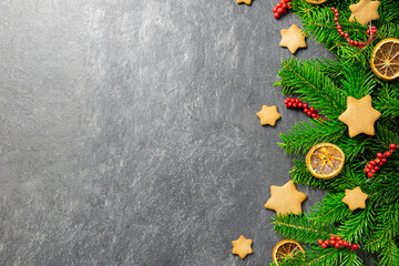 Fototapeta na wymiar Christmas traditional gingerbread stars with decoration, spices and christmas tree branches on a dark stone background. Top view. Copy space.