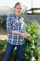 Portrait of smiling young woman working in garden at spring farm